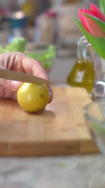 Dikey video. Bir adam limon keser. Tatlı olarak limon kesme işlemi. Yiyeceğe yakın çekim. Sıcak mutfak..