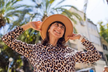 Güzel bir kadın güneşli bir günde kameraya bakar ve dışarıda gülümser. Şık aksesuarlar. Kız gülümsüyor, güzelliğini ve tarzını gösteriyor. Bahar havası.