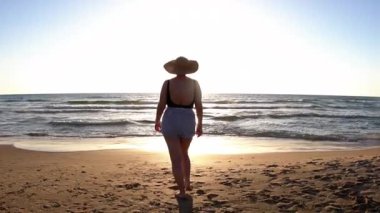 Vücut pozitifliği olan kız sahilde güzel bir gün batımının tadını çıkarıyor. Yaz havası. Sahildeki kız..