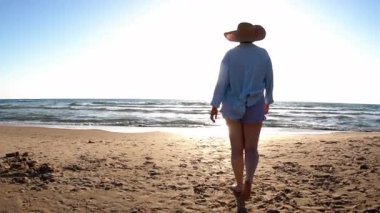 Vücut pozitifliği. Bir kız denize girer ve sahilde güzel bir günbatımının tadını çıkarır. Yaz havası. Plajda mayo giymiş bir kız..