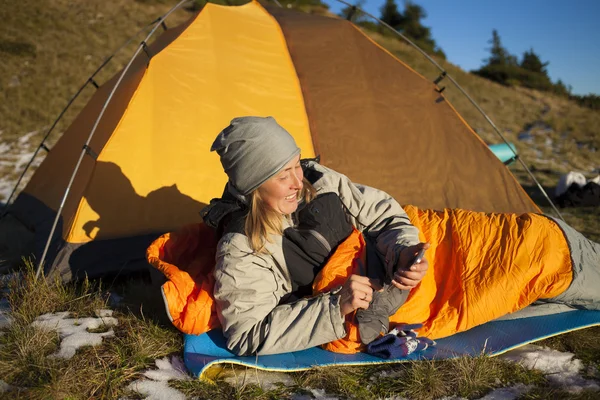 The girl with the phone lying in a sleeping bag. — Stock Photo, Image