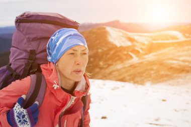 Kız bir sırt çantası ile yüksek bir dağın tepesine tırmanıyor.