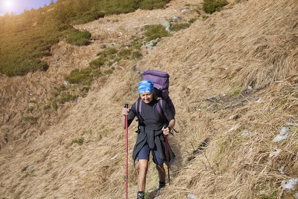 La fille avec le sac à dos va sur un sentier de montagne . — Photo