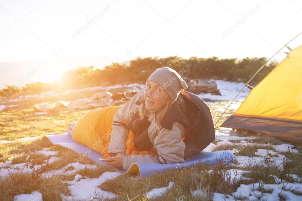 The girl with the phone lying in a sleeping bag.