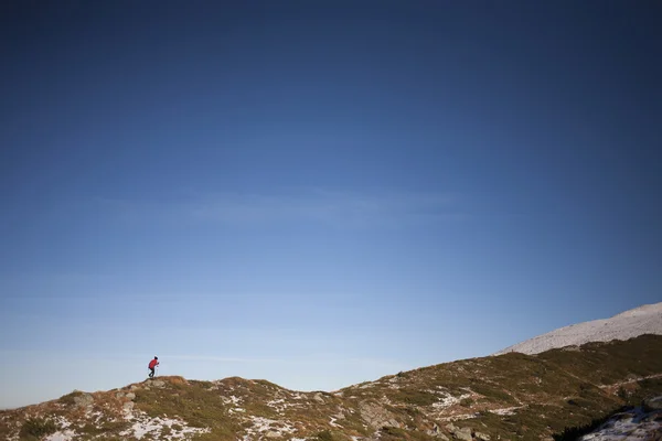 Mujer silueta que corre a lo largo de la cresta de la montaña . — Foto de Stock