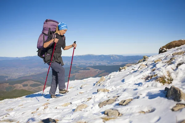 Klättrare med ryggsäck är snöiga backen. — Stockfoto