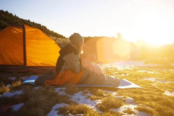 Bir uyku tulumu içinde oturan kız.