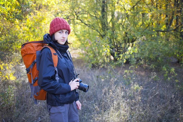 Uma menina com uma câmera e uma mochila — Fotografia de Stock