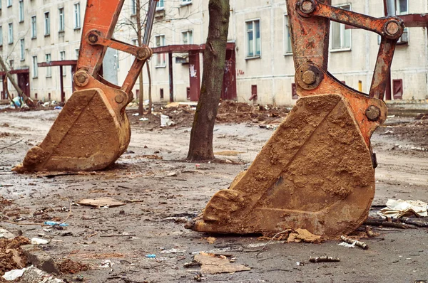 Buckets of the excavators standing on the dirty asphalt