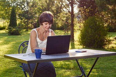 Kadın bahçe içinde laptop üzerinde çalışıyor