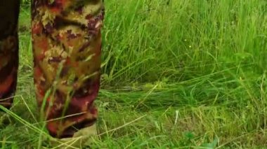 Çiftçi bir tırpan kullanarak çim biçme 