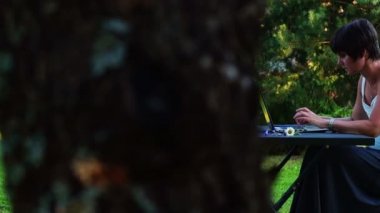 Bir dizüstü bilgisayar açık havada üzerinde çalışan oldukça orta yaşlı kadın