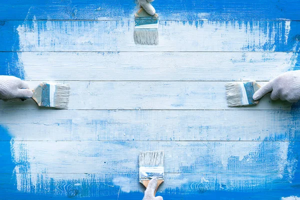 Kreativní Pozadí Čtyřmi Rukama Malovat Modré Dřevěné Desky Bílou Barvou — Stock fotografie