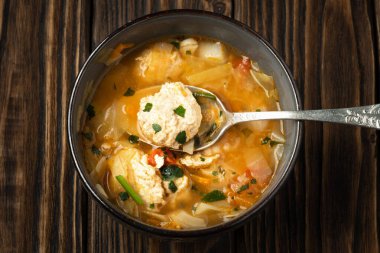 Köfteli tavuk çorbası ve koyu kahverengi ahşap tahtalar.