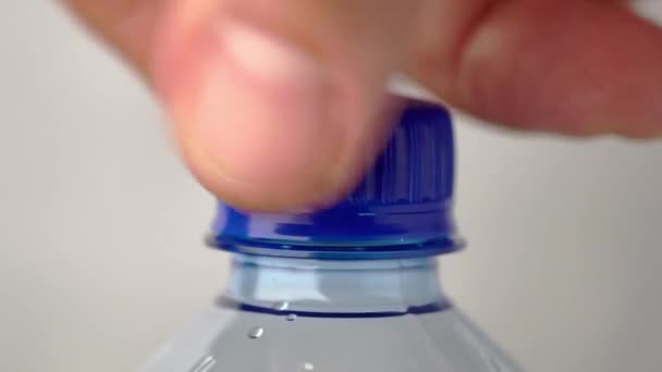 Mão masculina desparafusos e parafusos tampa de uma nova garrafa de plástico de água carbonatada de perto — Vídeo de Stock