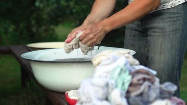 Mulher lava roupas com as mãos na bacia velha ao ar livre no campo no verão — Vídeo de Stock