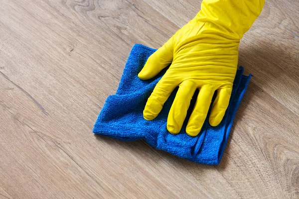 Mano in un guanto di gomma lavare un pavimento in laminato con un panno bagnato — Foto Stock