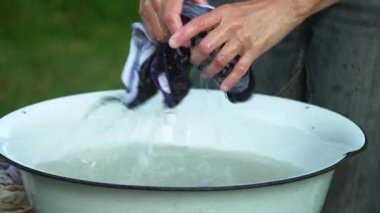 Yazın kırsal kesimde, eski havuzda elbiselerini yıkayıp yıkar ve yıkar.