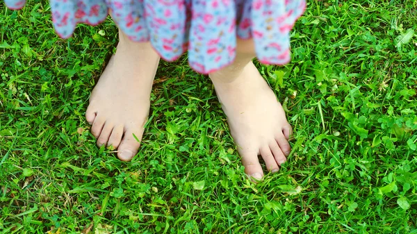 十岁女孩的脚在绿色的草地上 — 图库照片