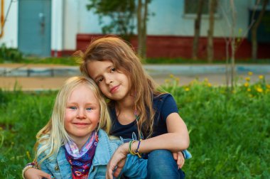 Küçük kız oturuyor çimlere kucaklayan