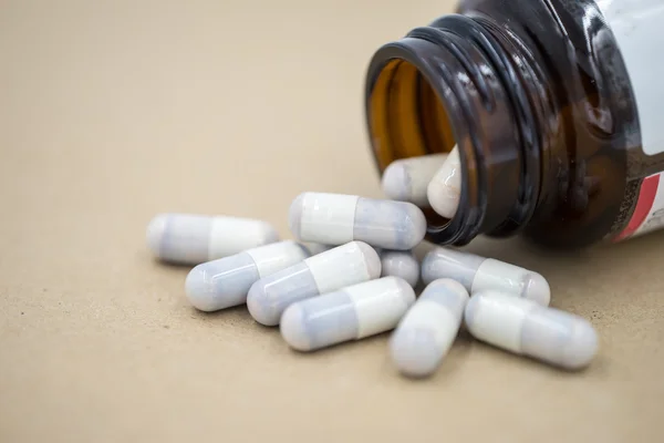 Herb capsules spilling out of a bottle. — Stock Photo, Image