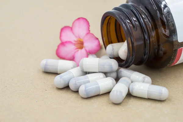 Herb capsules spilling out of a bottle. — Stock Photo, Image