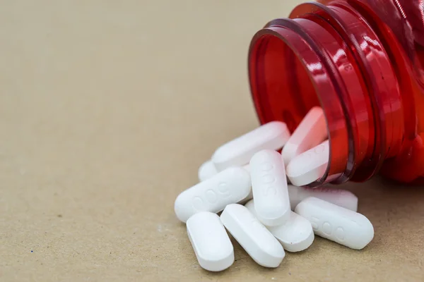 Herb capsules spilling out of a bottle. — Stock Photo, Image