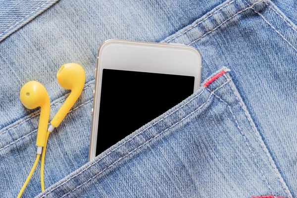 Closeup smartphone ve denim kot pantolon cebinde sarı kulaklık.