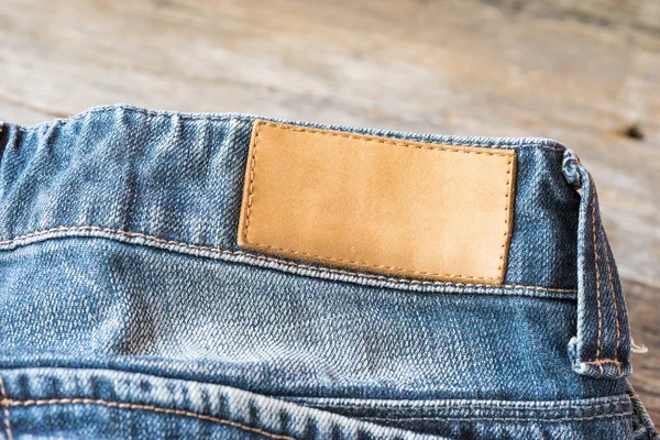 Tom läder etikett Blå jeans på trä bakgrund. — Stockfoto