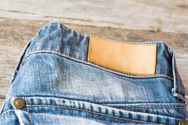 Tom läder etikett Blå jeans på trä bakgrund. — Stockfoto