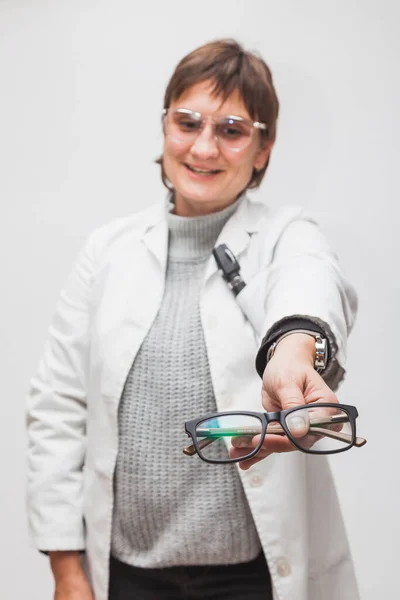 Bir gözlükçünün çalışanı müşteriye ilk bakışta görülen yeni gözlük verir. Gözlükler odaklanmış ve optometristin yüzü bulanık..