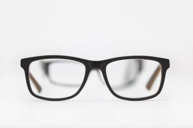 Beyaz bir yüzeye yerleştirilmiş iki çift gözlük. En yakınındakiler odak noktasında, diğerleri ise ilk bakışta görülür ve odak dışı kalır. Arkaplan beyaz.