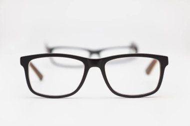 Beyaz bir yüzeye yerleştirilmiş iki çift gözlük. En yakın olanlar odak noktasında ve diğerleri bulanık. Arkaplan beyaz.