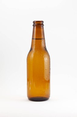 Beyaz arka planda yoğunlaşma damlaları olan kahverengi bira şişesi. Şişe açıldı ve metal bir kapağı yok..