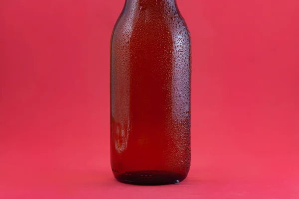 Часть Коричневой Бутылки Свежего Пива Капельками Конденсата Красном Фоне Бутылка — стоковое фото