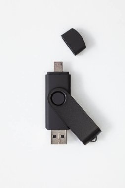 USB ve mikro USB portlu siyah kalem sürücüsü beyaz arka plana yerleştirilmiş. Küçük portun silinmiş bir kapağı var..