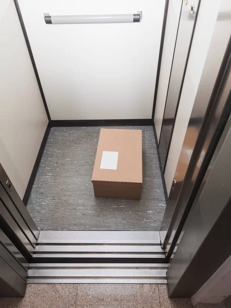 COVID-19 'un yayılmasını önlemek için alıcıya fiziksel yakınlıktan kaçınmak için asansörde bırakılan bir paket. Etiket kişiselleştirme için boş.