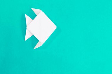 Origami balığı turkuaz mavi arka planda izole edildi.