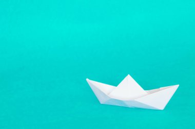 Origami teknesi turkuaz mavi arka planda izole edildi. Araç beyaz kağıttan yapılmıştır..