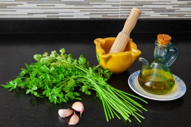 Siyah granit mutfak tezgahında havan, maydanoz, sarımsak ve zeytinyağı pişirmek..