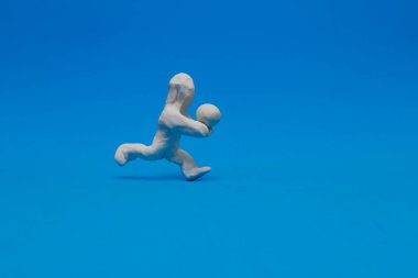 Beyaz plastik bebek mavi arka planda voleybol antrenmanı yapıyor. Bebek topu alıyor ve ona kollarıyla vuruyor..