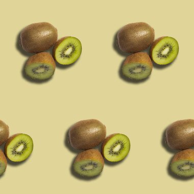 İki kivi meyvesinin kusursuz tekrarı. Bir tanesi ikiye bölünmüş, yeşil eti ve siyah tohumları ortaya çıkıyor. Meyve sarı arka plana konur.