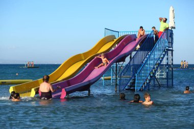 Bayanlar mil plajı, Kıbrıs - 20 Temmuz 2021: Çocuklar atlıyor ve sahilde su kaydırağında eğleniyorlar