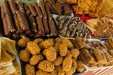 Bir fırın ve pastanenin penceresini çeşitli yeni pişmiş yerel tatlılarla göster: kurabiyeler, bisküviler, şekerler.