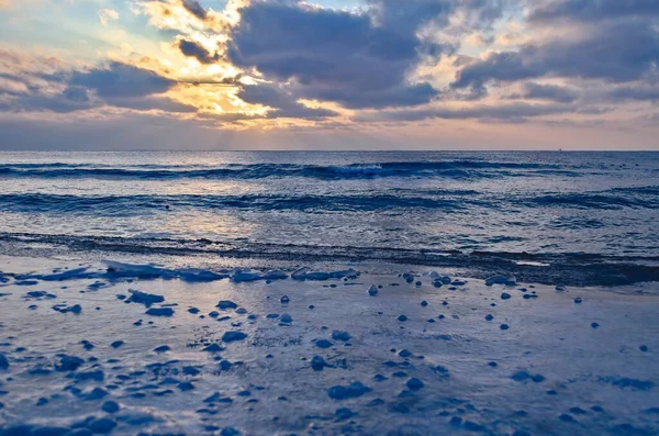 凍結した海岸は海によって夕日の背景に氷で覆われています 寒さの背景 — ストック写真