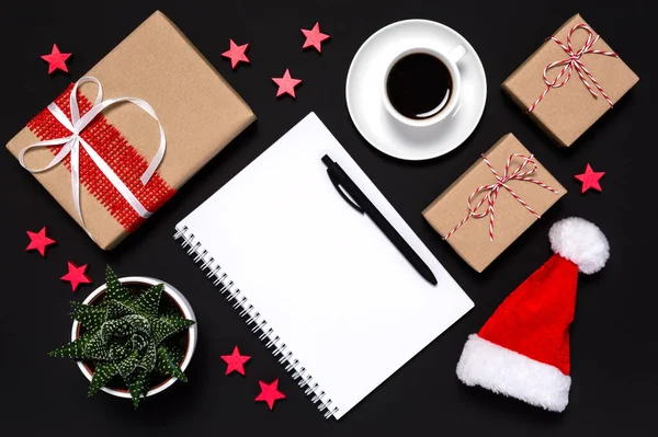 Writing letter to Santa. Blank notebook with copy space for wish list, goals, new year resolution, gifts, red Santas hat, stars and coffee cup on black background. Christmas and new year flat lay — Stock Photo, Image