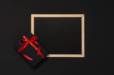 Kırmızı kurdeleli siyah hediye ve boş tahtalı yay. Noel, Sevgililer Günü ya da doğum günü hediyeli tatil şablonu. Kara Cuma indirimi. Düz konum, metin için boşluk kopyala