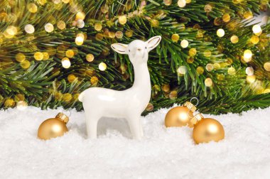 Beyaz Noel geyiği ve arka planda çam ağacı ve bokeh olan altın toplar. Bayramlık tebrik kartı. Mutlu Noeller ve yeni yıl