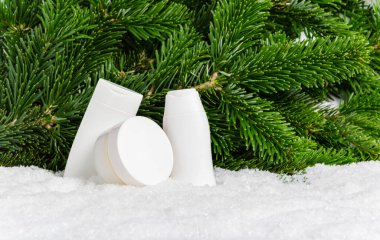 Beyaz kış cilt bakımı kozmetik ürünleri ve Noel ağacı dalları. Yüz kremi kavanozu, vücut losyonu, süt ve temizlik şişeleri. Organik cilt nemlendirici ve besleyici maske modeli