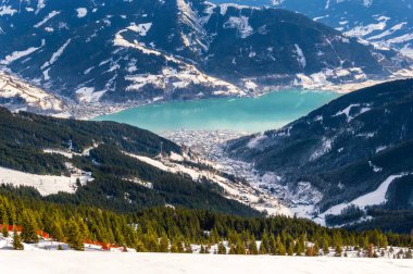 Zell am See and Schmitten town at Zeller lake in winter. View from Schmittenhohe mountain, snowy ski resort slope in the Alps mountains, Austria. Stunning landscape, snow and forest sky near Kaprun